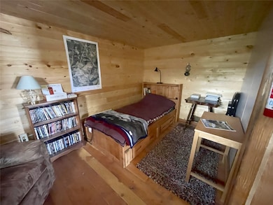 Bedroom with wood ceiling, wood walls, and wood finished floors