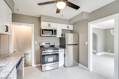 Kitchen featuring light wood-type flooring, white cabinets, ceiling fan, light stone countertops, and appliances with stainless steel finishes