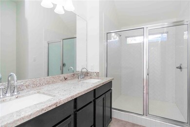 Bathroom featuring double vanity, a stall shower, and light tile patterned floors