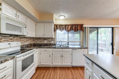 Kitchen with white appliances, a wealth of natural light, white cabinetry, and sink