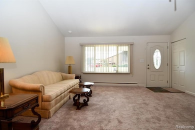 Carpeted living room with vaulted ceiling and a baseboard heating unit