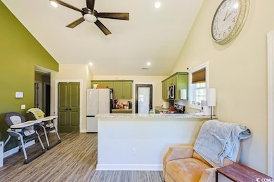 Kitchen with green cabinets, stainless steel appliances, recessed lighting, light wood-style floors, and high vaulted ceiling