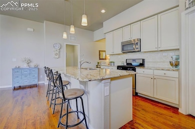 Kitchen featuring a sink, wood finished floors, stainless steel appliances, visible vents, and decorative backsplash