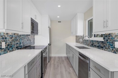 Kitchen featuring appliances with stainless steel finishes, white cabinets, light wood-style floors, light stone counters, and recessed lighting