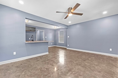 Unfurnished living room with a ceiling fan and finished concrete flooring