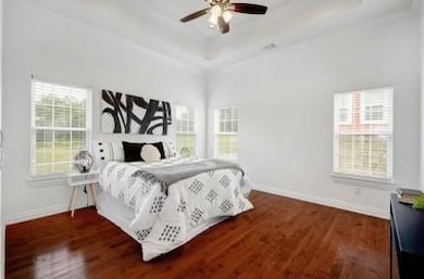 Bedroom with baseboards, a ceiling fan, a tray ce