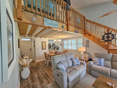 Living area featuring a chandelier, stairs, wood finished floors, and baseboards