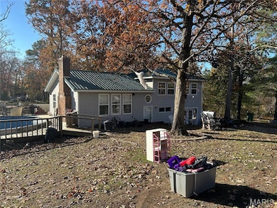 View of front of property with a chimney, a metal roof, and a deck