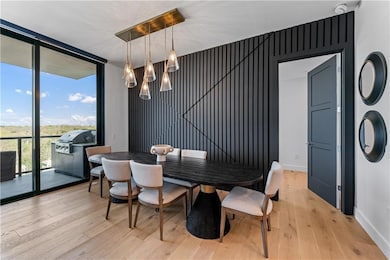 Dining area with a wall of windows, a chandelier, and light wood-style floors
