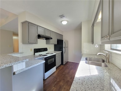 Kitchen featuring gray cabinets, electric range, dark wood-type flooring, light stone countertops, and under cabinet range hood