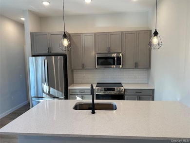 Kitchen featuring appliances with stainless steel finishes, gray cabinetry, light stone countertops, tasteful backsplash, and recessed lighting
