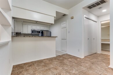 Kitchen featuring white cabinets, a peninsula, stainless steel appliances, and light tile patterned floors