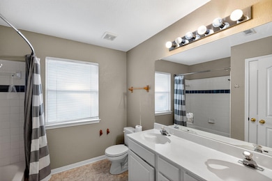 Full bathroom with shower / bath combo with shower curtain, double vanity, and light tile patterned floors