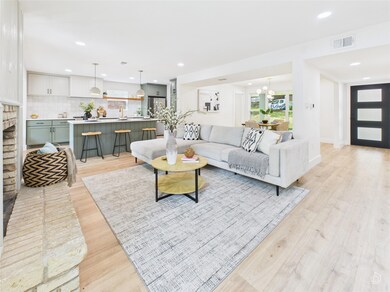 Living area with light wood-style flooring, recessed lighting, a chandelier, and a brick fireplace