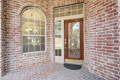 Great covered front porch with a brick patio and a beautiful front door surrounded by windows
