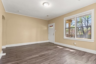 Interior space with visible vents, baseboards, a textured ceiling, crown molding, and dark wood finished floors
