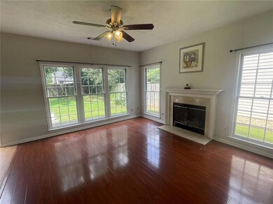 Unfurnished living room with a glass covered fireplace, hardwood / wood-style flooring, ceiling fan, and healthy amount of natural light
