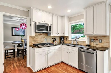 Kitchen featuring stainless steel appliances, a sink, crown molding, dark stone countertops, and white cabinetry
