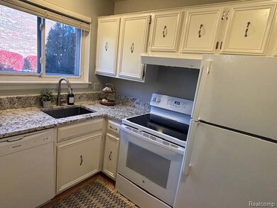 Kitchen with white appliances, white cabinets, light stone counters, and under cabinet range hood
