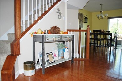 Hardwood floors extend from open hall area to dini