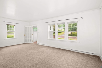 Empty room with baseboard heating, carpet floors, and french doors