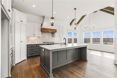 Kitchen featuring a center island with sink, light countertops, custom range hood, and a sink