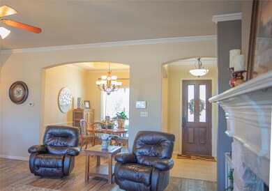 Entrance foyer featuring arched walkways, wood finished floors, healthy amount of natural light, crown molding, and a chandelier