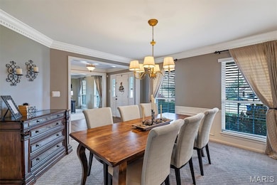 Dining space with ornamental molding, light colored carpet, and a chandelier