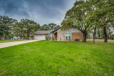 View of front of home with driveway, a garage, a front lawn, stone siding, and brick siding