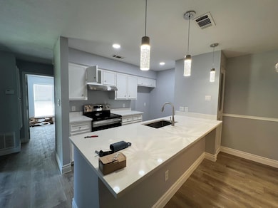 Kitchen with visible vents, a peninsula, stainles
