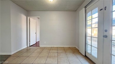Unfurnished room featuring a textured ceiling, french doors, and light tile patterned floors