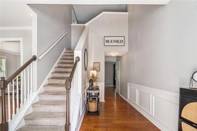 Stairway with wood finished floors, a wainscoted wall, crown molding, and a decorative wall