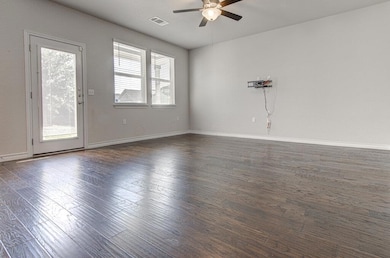 Empty room featuring ceiling fan, dark wood finis