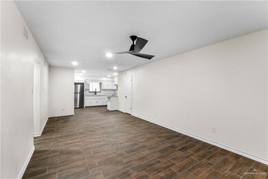 Unfurnished living room featuring ceiling fan, baseboards, dark wood-style flooring, recessed lighting, and a sink