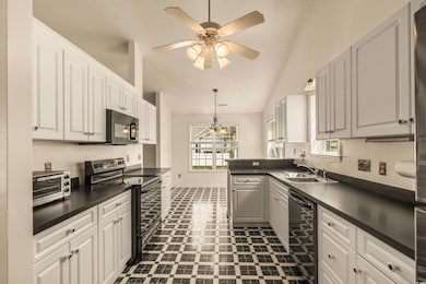 Kitchen with a wealth of natural light, a sink, black appliances, and dark countertops