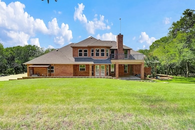 Rear view of property featuring a patio area, roof with shingles, brick siding, and a yard