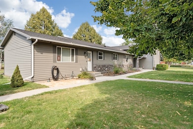 View of front of property with a front lawn, a shingled roof, and stone siding