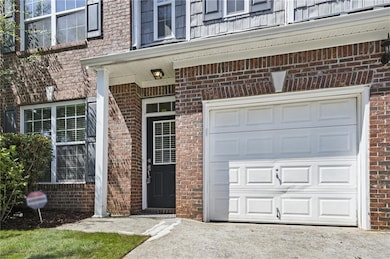 Doorway to property with brick siding, an attached garage, and asphalt driveway