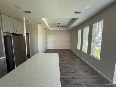 Kitchen with freestanding refrigerator, a tray ceiling, ceiling fan, baseboards, and gray cabinetry
