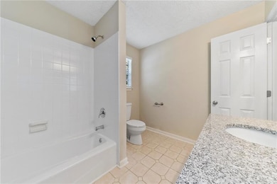 Full bathroom featuring a textured ceiling, tile p