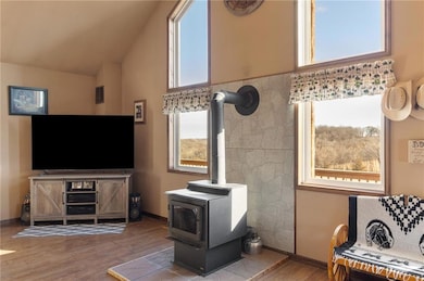 Living area with a wood stove, wood finished floors, baseboards, and high vaulted ceiling