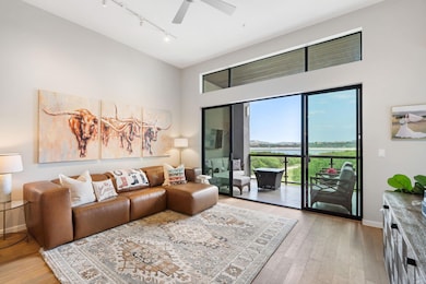 Living area featuring a water view, light wood finished floors, track lighting, and a ceiling fan