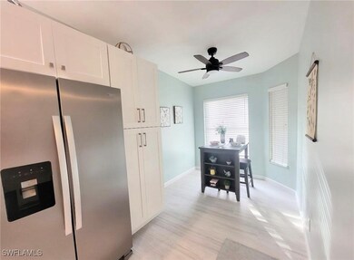 Kitchen featuring stainless steel refrigerator with ice dispenser, light wood-style flooring, white cabinetry, and ceiling fan