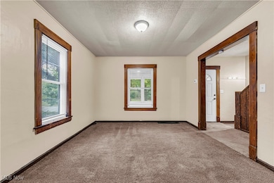 Spare room featuring a textured ceiling and light colored carpet