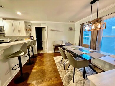 Dining area featuring dark wood-type flooring, baseboards, visible vents, ornamental molding, and an inviting chandelier