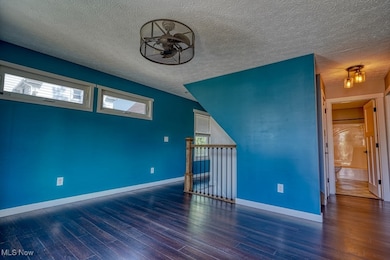Empty room with wood finished floors and a textured ceiling