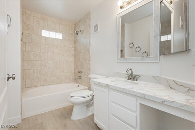 Guest bathroom with updated tile surround, quartz counter tops, new mirror, toilet, sink and faucet.