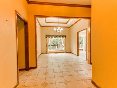 Tiled empty room featuring a notable chandelier, crown molding, and a raised ceiling