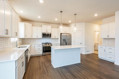 (Actual photo of the home) This spacious kitchen features a large center island, quartz countertops, LVP floors, stainless appliances and more.
