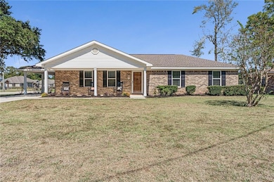 Ranch-style house featuring covered porch, a front lawn, brick siding, and an attached carport